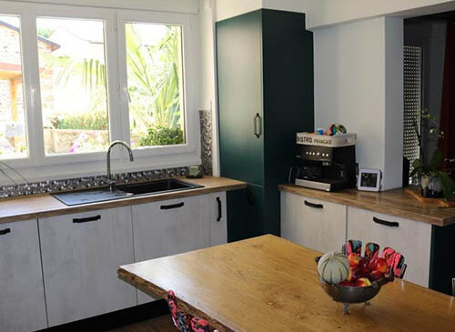 Cuisine moderne et chic en U avec un ilot central, parfait pour une famille, avec façades béton blanc, plan de travail en chêne brut et poignées noires